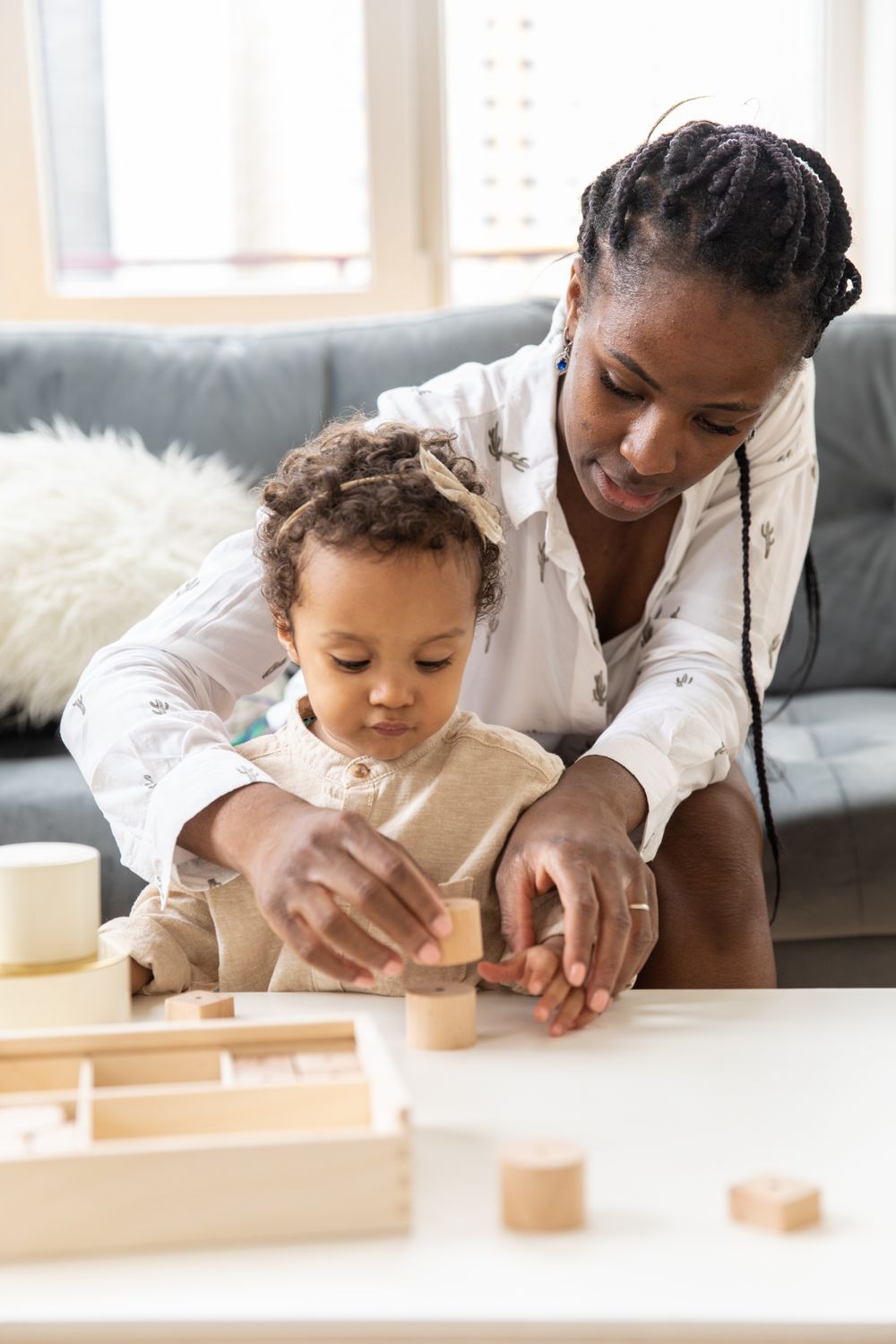 Madre ayudando al niño a jugar con bloques de madera en casa